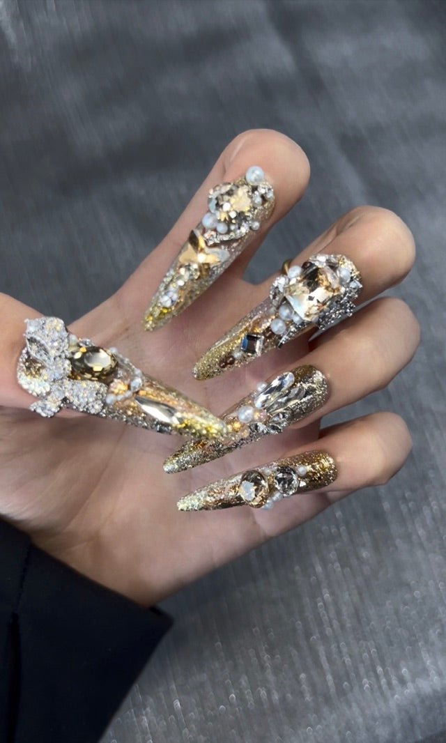 Gold crystal press-on nails catching light in a close-up photo